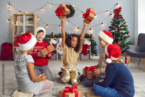 Group of happy, excited, multiracial kids, friends or step siblings, exchanging presents at home