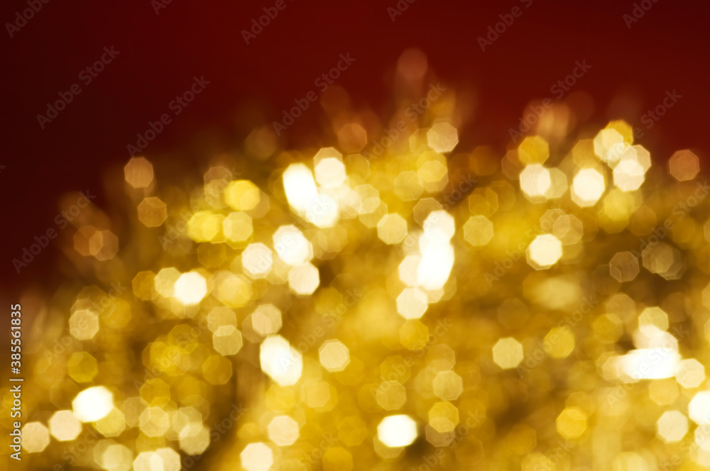 Christmas and New Year holidays blurred golden sparkles on red background, abstract background with bokeh defocused glittering lights and shadow