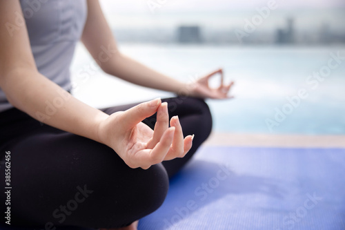Woman Practicing Yoga with Sukhasna Pose Near the Pool