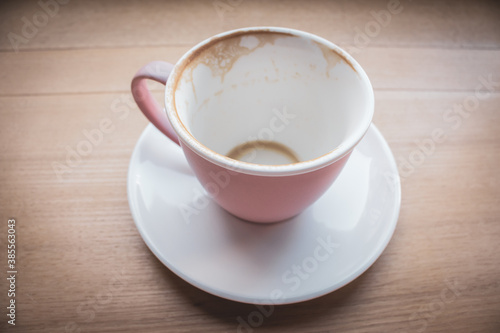 Empty cup of cappuccino, top view. Pink cup of coffee on wooden table. Empty coffee mug on white plate. Breakfast concept. Finish of dinner. Coffee cup isolated.