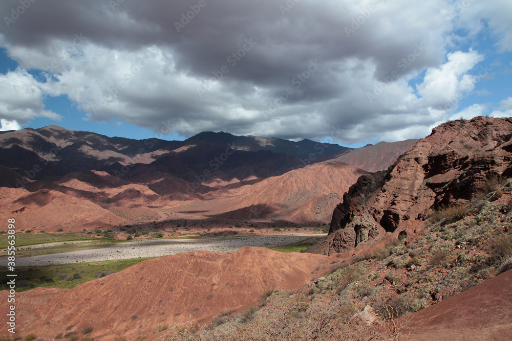 Desert landscape. Geology.View of the beautiful green valley surrounded by the red canyon and mountains under a blue sky.