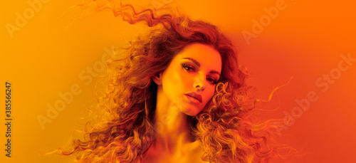 Woman in colorful neon gold light, Fashion make-up. Beautiful blond girl, stylish curly hair, trendy makeup. Creative beauty portrait, fashionable model, voluminous hairstyle