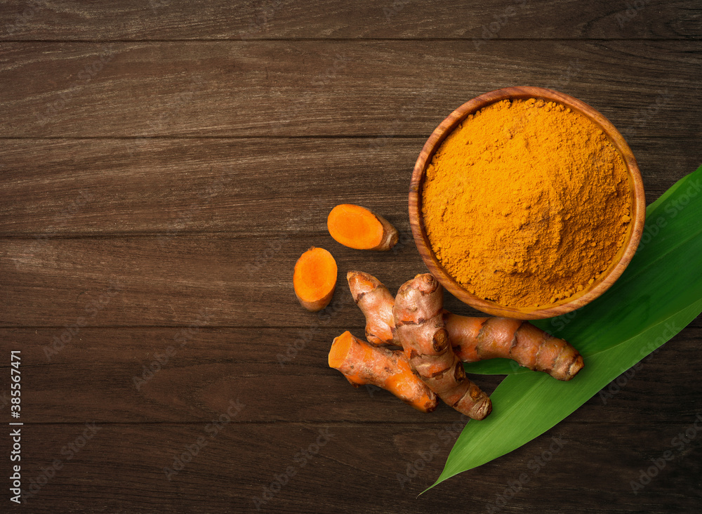 Top view (flat lay) of finely dry Turmeric powder with rhizome sliced on wooden table. Top view (flat lay) of finely dry Turmeric powder with rhizome sliced on wooden table.