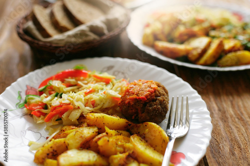 A simple meal on a plate at a diner. Salad, fried potatoes and meat cutlet. Quick and delicious lunch