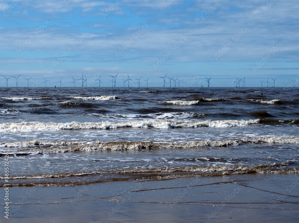 the beach at blundell flats in southport with waves braking on the beach and the wind turbines at burbo bank visible in the distance the beach at blundell flats in southport with waves braking on the beach and the wind turbines at burbo bank visible in the distance