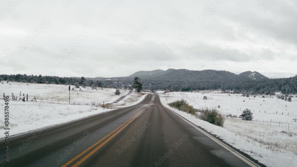 Driving on Empty Highway After Fresh Snowfall with Mountains in the Distance Driving on Empty Highway After Fresh Snowfall with Mountains in the Distance