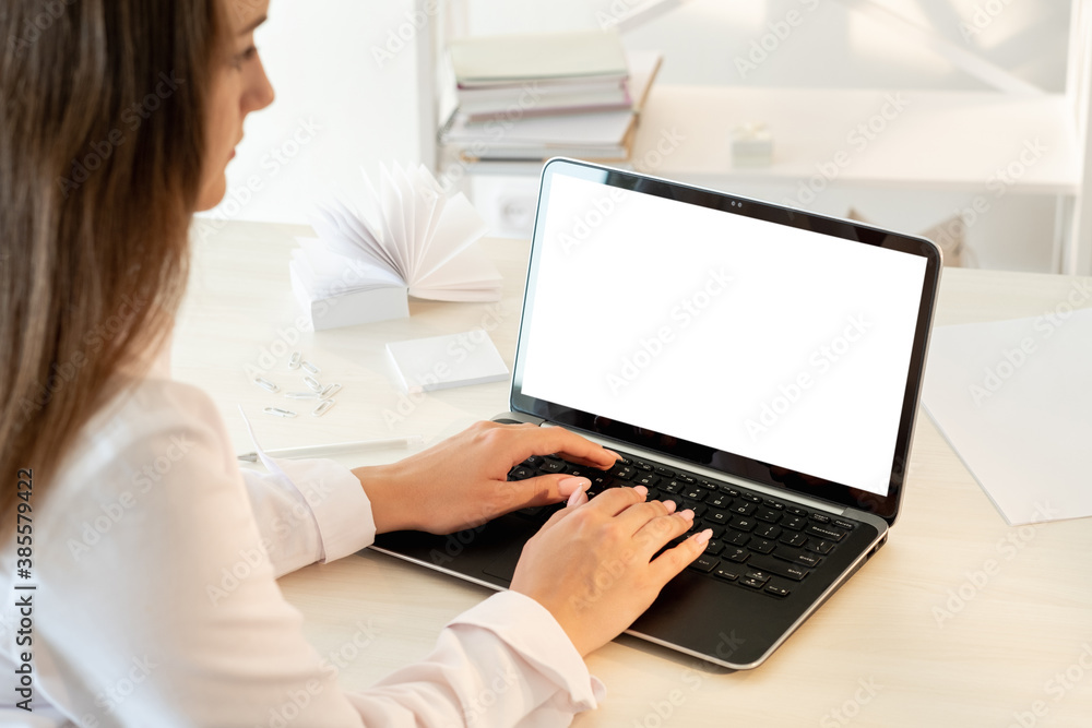 Distance work. Freelance workplace. Business communication. Woman in white shirt typing on laptop blank screen modern light interior copy space.