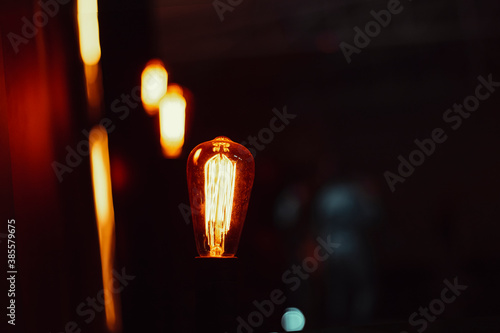 Filament lamp lit with black background, emitting light and brightening the environment photo