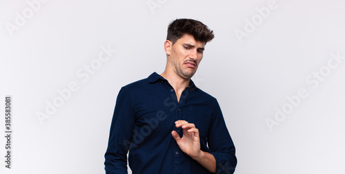 Quadro em tela young handsome man feeling disgusted and nauseous, backing away from something n