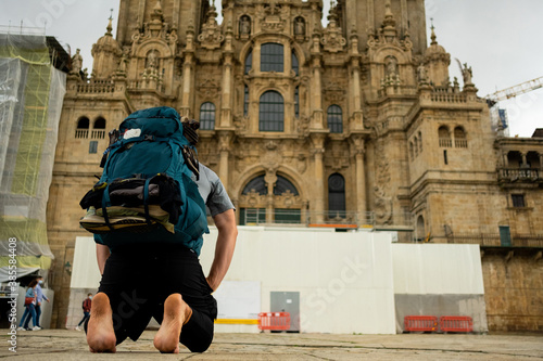 camino de santiago pilgrim kneeling in front of santiago cathedral after finish the pilgrimage, praying bare feet in plaza del obradeiro photo