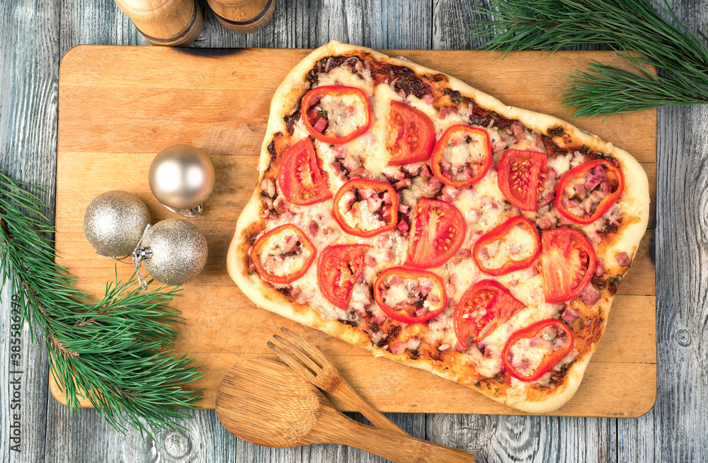 Christmas table with pizza and pine branches on a wooden background. The view from the top. The concept of New year and Christmas. Christmas table with pizza and pine branches on a wooden background. The view from the top. The concept of New year and Christmas.