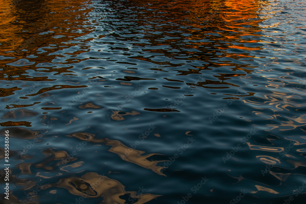 Orange red reflections in blue water. Ships, rusty barges in the light of the sunset Orange red reflections in blue water. Ships, rusty barges in the light of the sunset