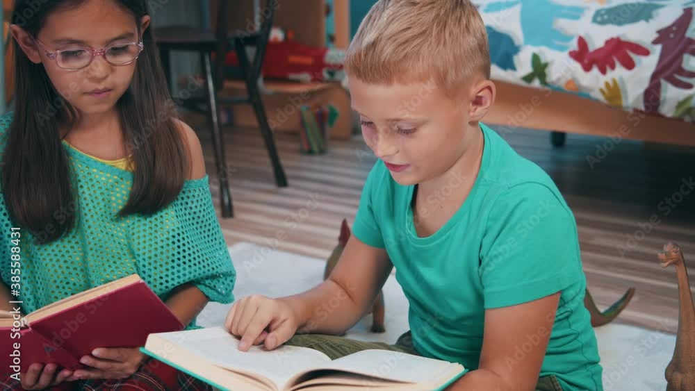 Couple of cheerful preschool kids brother and sister reading story books discussing pictures. Lovely children. Home entertainment. Playing time. Couple of cheerful preschool kids brother and sister reading story books discussing pictures. Lovely children. Home entertainment. Playing time.