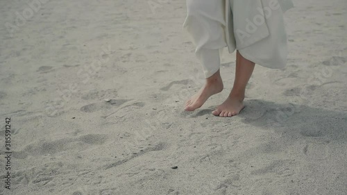 Front view of woman legs and feet walking on sandy beach to the sea on sunny day. Media. Slim pretty girl goes by the sea on clear white sand. Female do sporta at free air. photo