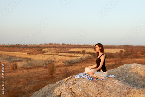 Woman meditating yoga alone at sunrise mountains.