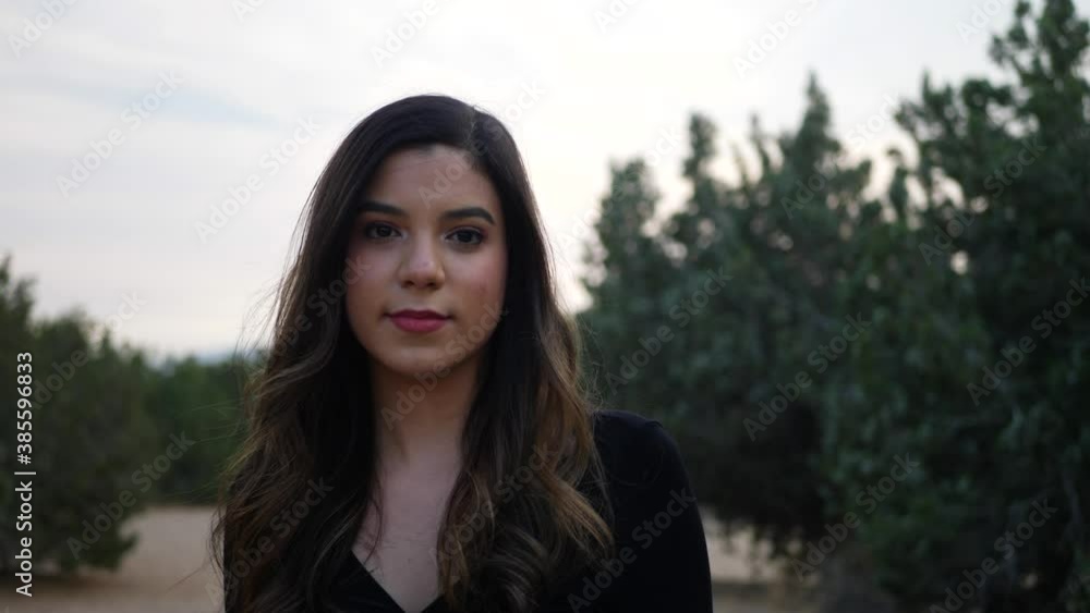 Beautiful young independent adult hispanic woman outdoors staring at the camera with a serious, calm and strong feeling. Beautiful young independent adult hispanic woman outdoors staring at the camera with a serious, calm and strong feeling.