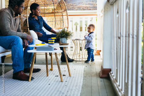 Black family play with child on front porch of family home