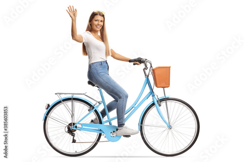 Young female with long hair riding a bicycle and waving
