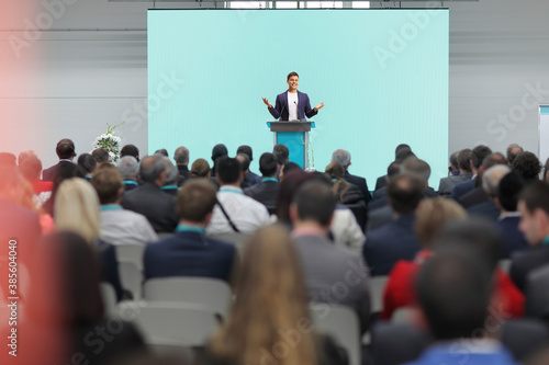 Man speaking on a pedestal on a conference in front of an audience photo