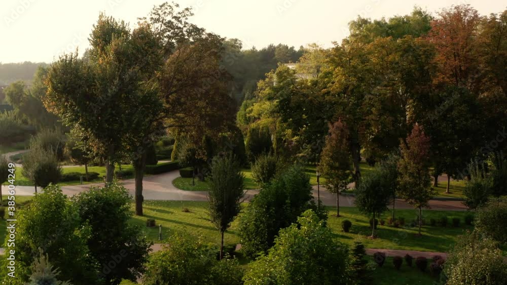 Aerial view of the city park on a sunny autumn evening. Park with walking people, paths, trees and green grass. Landscaping. Place for walking and outdoor recreation Aerial view of the city park on a sunny autumn evening. Park with walking people, paths, trees and green grass. Landscaping. Place for walking and outdoor recreation