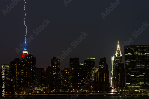 Canvas Print Lighting striking the Empire State Building in New York City midtown Manhattan skyline from Long Island City, Queens across the East River