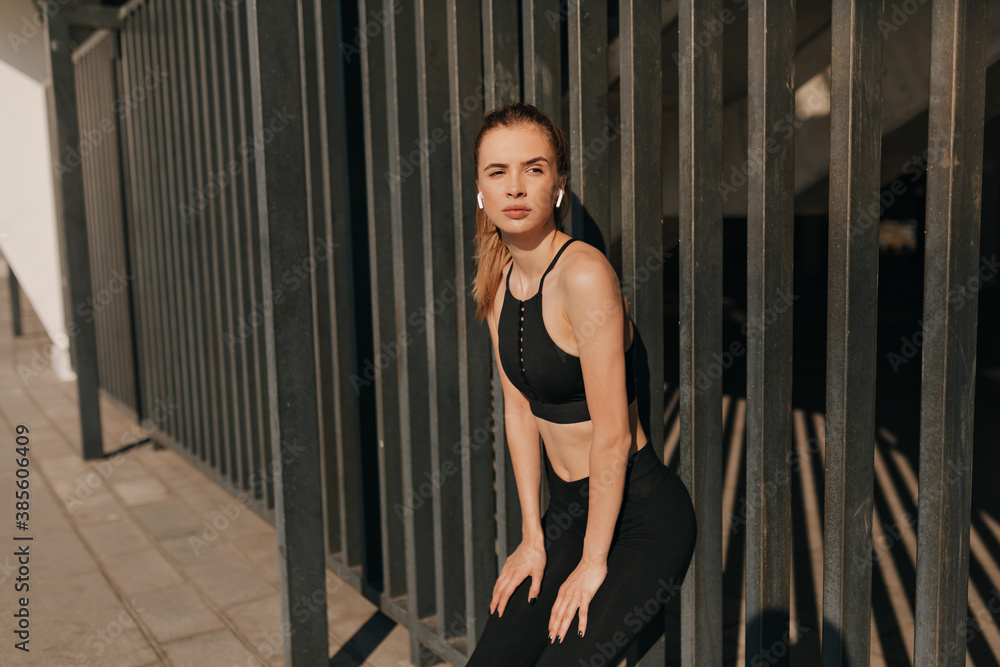 Image of smiling fitness woman in headphones working out and running at sport square Image of smiling fitness woman in headphones working out and running at sport square