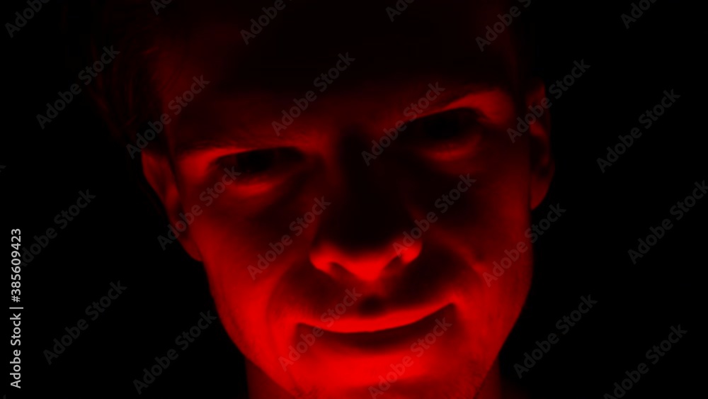 A scary and evil criminal man attacking a victim with a crazy smile and a look of violence and terror out of the dark night. A scary and evil criminal man attacking a victim with a crazy smile and a look of violence and terror out of the dark night.