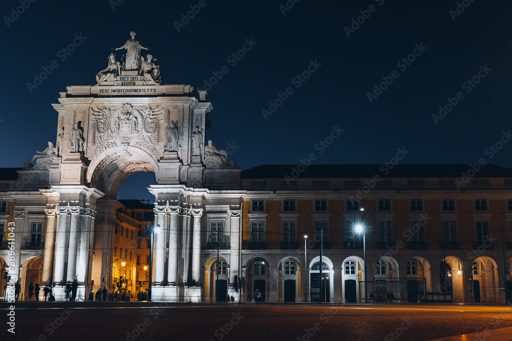 Obraz premium Lisboa, Portugal 9.10.2020 Rue Augusta arch in Commerce square at night at Praca do Comercio. sculptures of Viriatus, Vasco da Gama, Pombal, Nuno Alvares Pereira. Tourist people silhouette, trams