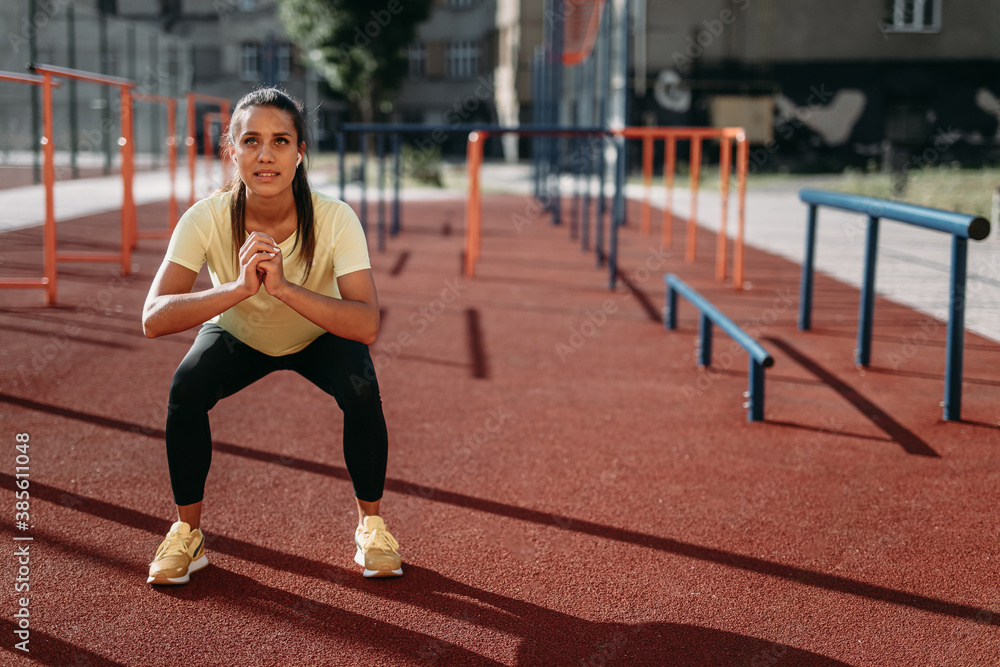 Fototapeta premium Young woman in sport outfit training legs at stadium