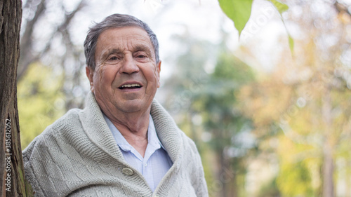 Portrait of happy senior man smiling, in the public park, outdoors. Old man relaxing outdoors and looking at camera. Portrait of elderly man enjoying retirement