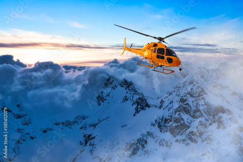Yellow Helicopter flying over the Rocky Mountains during a colorful sunset. Aerial Landscape from British Columbia, Canada near Vancouver. Epic Adventure Composite