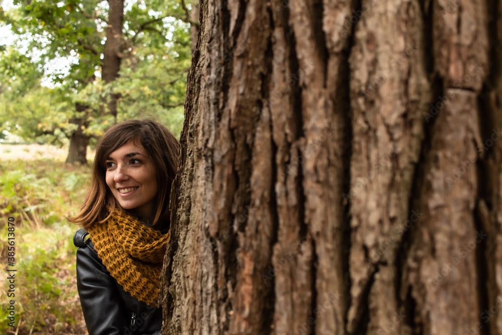 Detail picture of an attractive young female with a black leather jacket located close to an oak's trunk Detail picture of an attractive young female with a black leather jacket located close to an oak's trunk