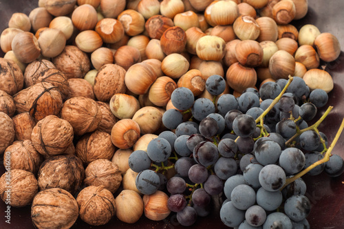 Ripe raw hazelnuts, walnuts and red grape closeup as food background