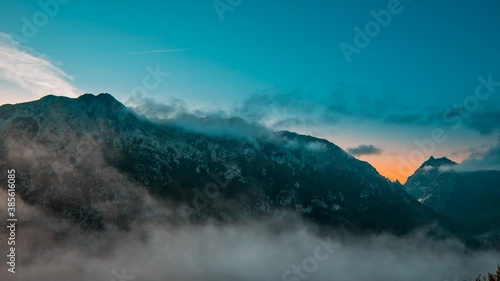 Sunrise in the mountains in time lapse, the fogs change shape quickly and the sunlight shows spectacular orange tones.