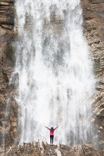 Woman raising her arms under a large natural waterfall