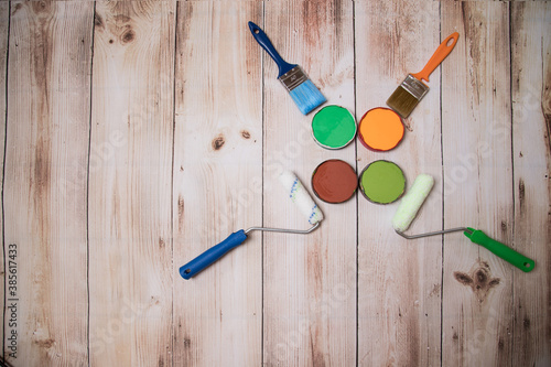 Paints, brushes and rollers for painting are laid out in the form of a still life on a wooden background.The concept of DIY repair. A place for a copy of space. Horizontal orientation