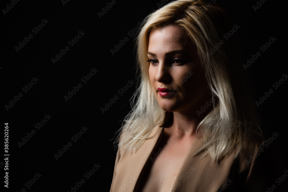 Young beautiful blond glamorous woman in black over dark background Young beautiful blond glamorous woman in black over dark background