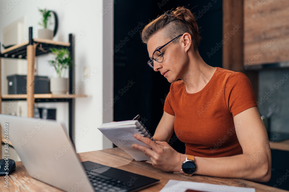 Beautiful woman writing notes while working from home. Beautiful woman writing notes while working from home.