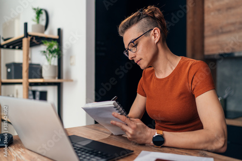 Beautiful woman writing notes while working from home.