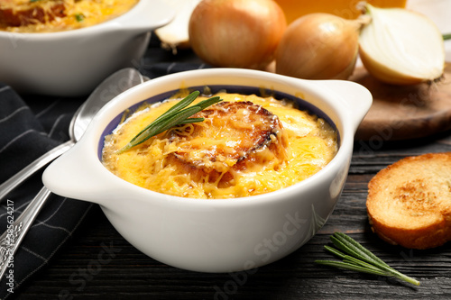 Tasty homemade french onion soup served on black wooden table