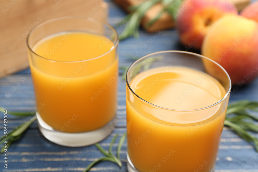 Glasses of natural peach juice on blue wooden table, closeup Glasses of natural peach juice on blue wooden table, closeup