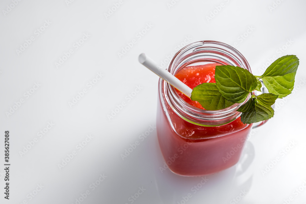Watermelon smoothie in a jar with mint leaves and a cocktail straw