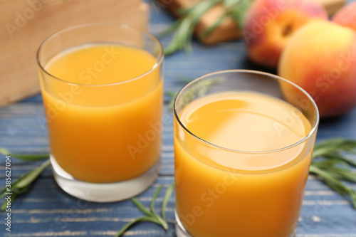 Glasses of natural peach juice on blue wooden table, closeup