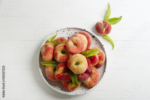 Fresh ripe donut peaches on white wooden table, flat lay