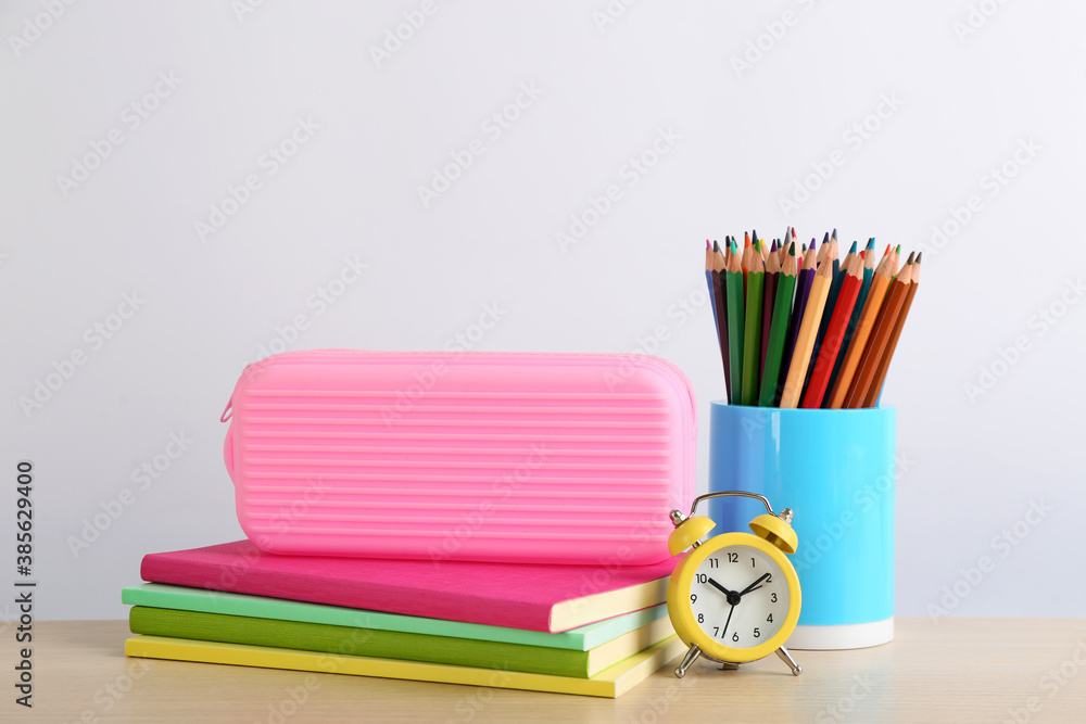Different school stationery and alarm clock on table against white background. Back to school