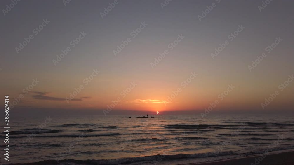 sunset on a beach. silhouette fishermen on a rock in the sea sunset on a beach. silhouette fishermen on a rock in the sea
