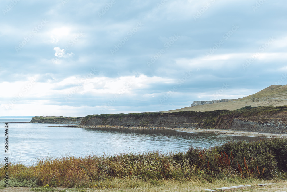 View of Kimmeridge Bay, Dorset UK, landscape vista shot of calm ocean water, dramatic overcasted sky