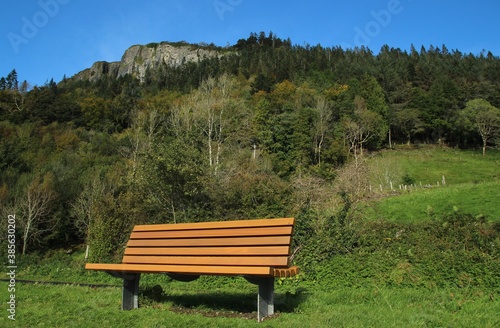 Wooden bench at roadside, Glencar, County Leitrim, Ireland with Kings Mountain in background against backdrop of blue sky