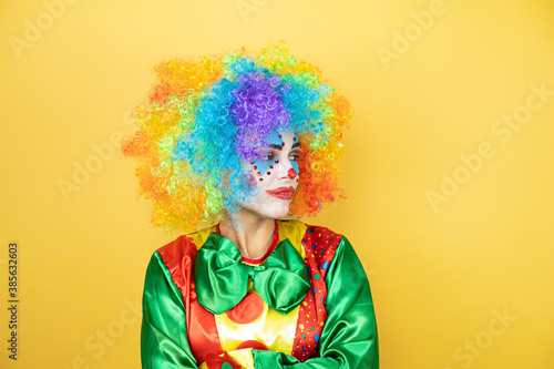 Clown standing over yellow insolated yellow background thinking looking tired and bored with crossed arms