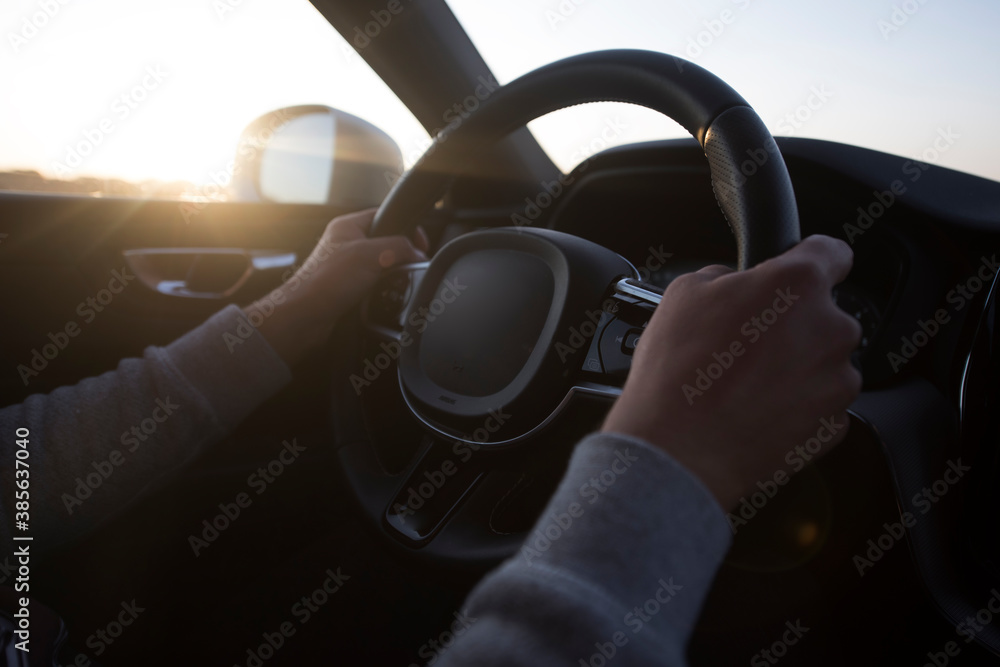Success in motion. Handsome young man driving a car at highway during sunset.
